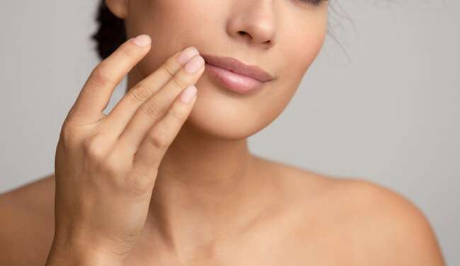 Woman touching the side of her upper lip